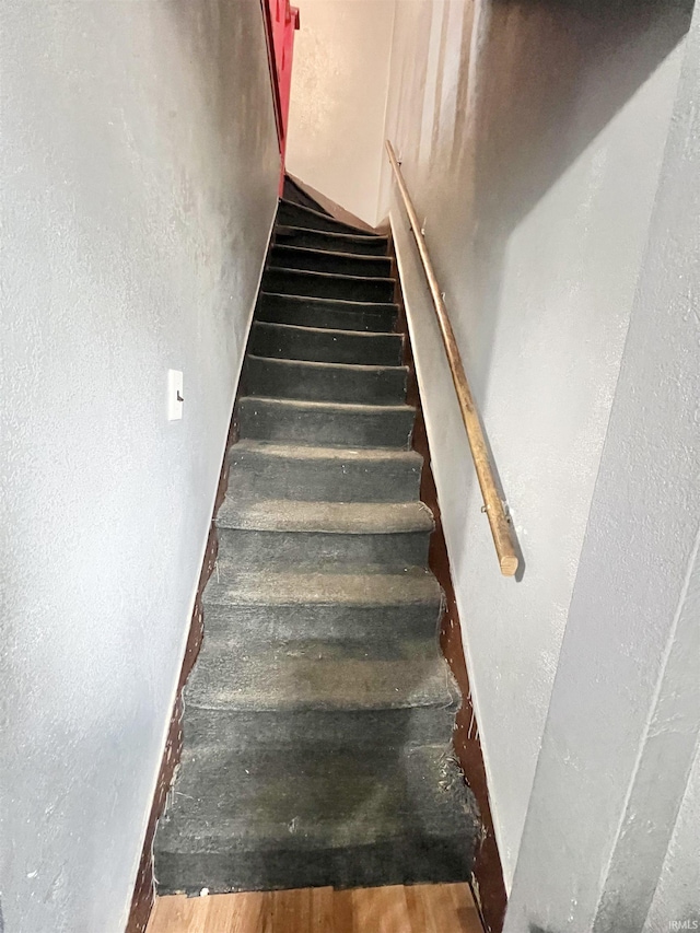 stairway with a textured wall and wood finished floors