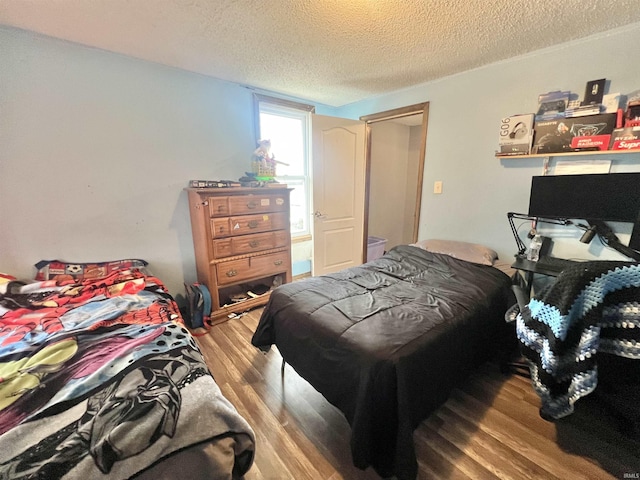 bedroom with a textured ceiling and wood finished floors