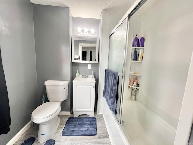 bathroom featuring toilet, vanity, a shower with door, and baseboards