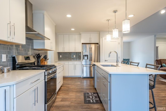 kitchen with stainless steel appliances, a breakfast bar, a sink, wall chimney range hood, and dark wood-style floors