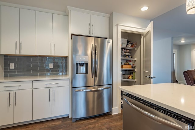 kitchen with stainless steel appliances, light countertops, dark wood finished floors, and tasteful backsplash