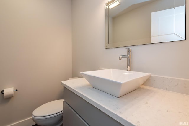 bathroom featuring toilet, baseboards, and vanity