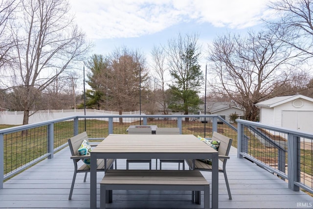 wooden terrace with outdoor dining space, a fenced backyard, an outbuilding, and a shed