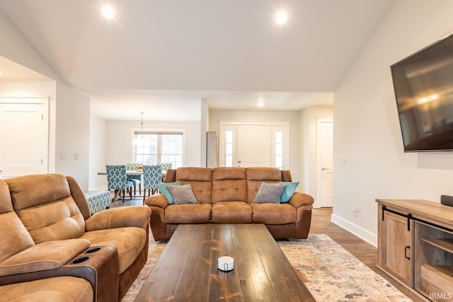 living room featuring lofted ceiling, recessed lighting, baseboards, and wood finished floors