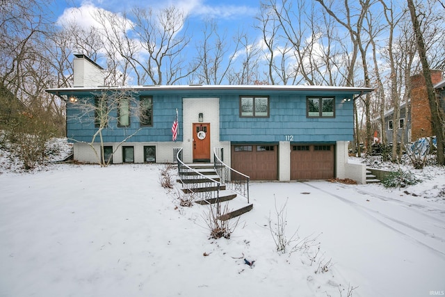 split foyer home with brick siding, a chimney, and an attached garage