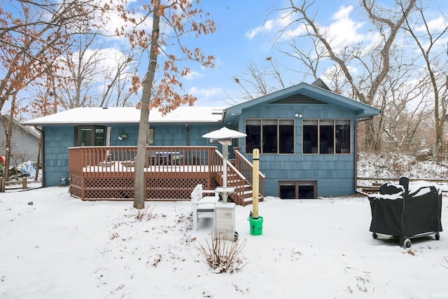 snow covered back of property featuring a wooden deck