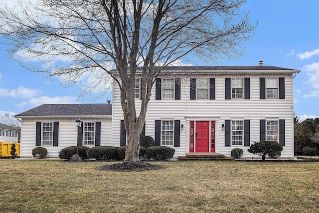 colonial house featuring a chimney and a front lawn