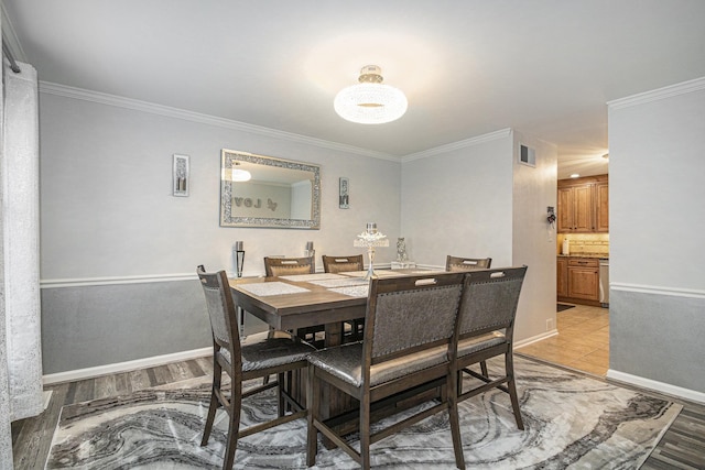 dining area featuring light wood-type flooring, visible vents, crown molding, and baseboards