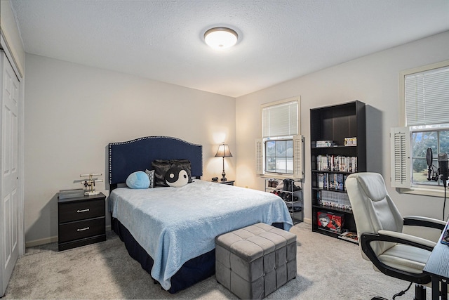 bedroom with a closet, carpet flooring, a textured ceiling, and baseboards