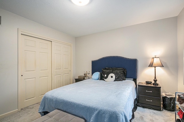 bedroom with a closet, light carpet, and baseboards