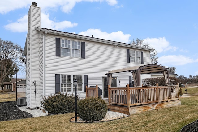 back of house featuring a deck, central AC, a chimney, and a lawn