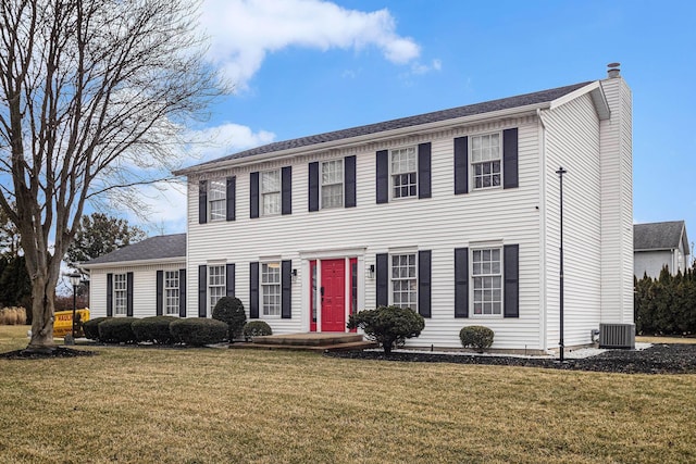 colonial home with a front lawn, a chimney, and cooling unit