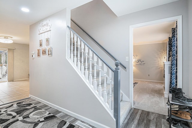 staircase featuring wood finished floors, visible vents, and baseboards