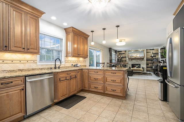 kitchen featuring a warm lit fireplace, a peninsula, open floor plan, appliances with stainless steel finishes, and brown cabinetry