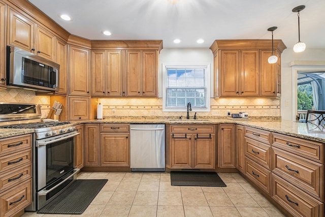 kitchen featuring appliances with stainless steel finishes, brown cabinets, a sink, and light tile patterned flooring