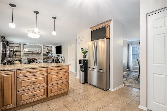 kitchen with hanging light fixtures, light stone counters, light tile patterned flooring, and freestanding refrigerator