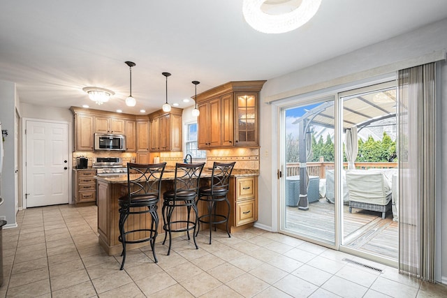 kitchen with visible vents, a breakfast bar, brown cabinets, a peninsula, and stainless steel appliances