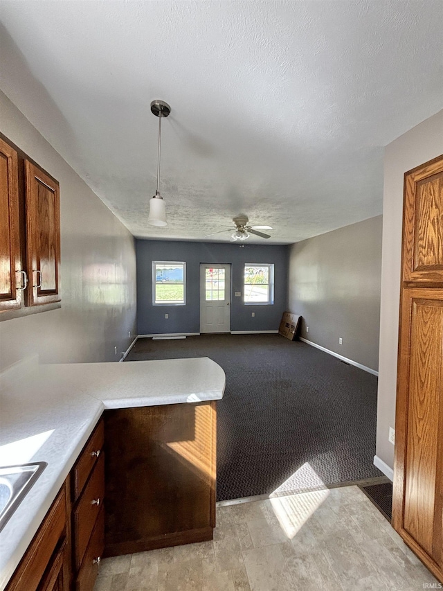 kitchen featuring light countertops, a sink, a peninsula, and a textured ceiling