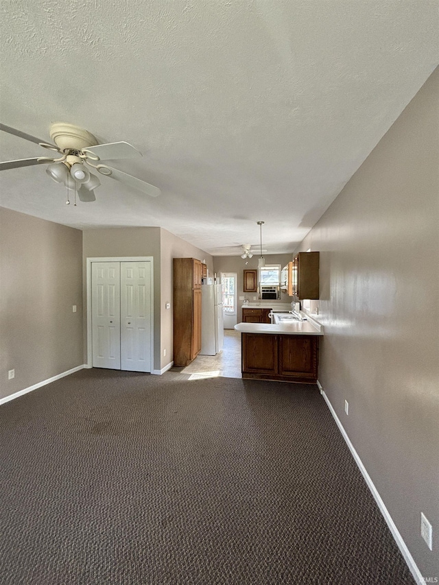 kitchen with freestanding refrigerator, open floor plan, light countertops, and dark colored carpet