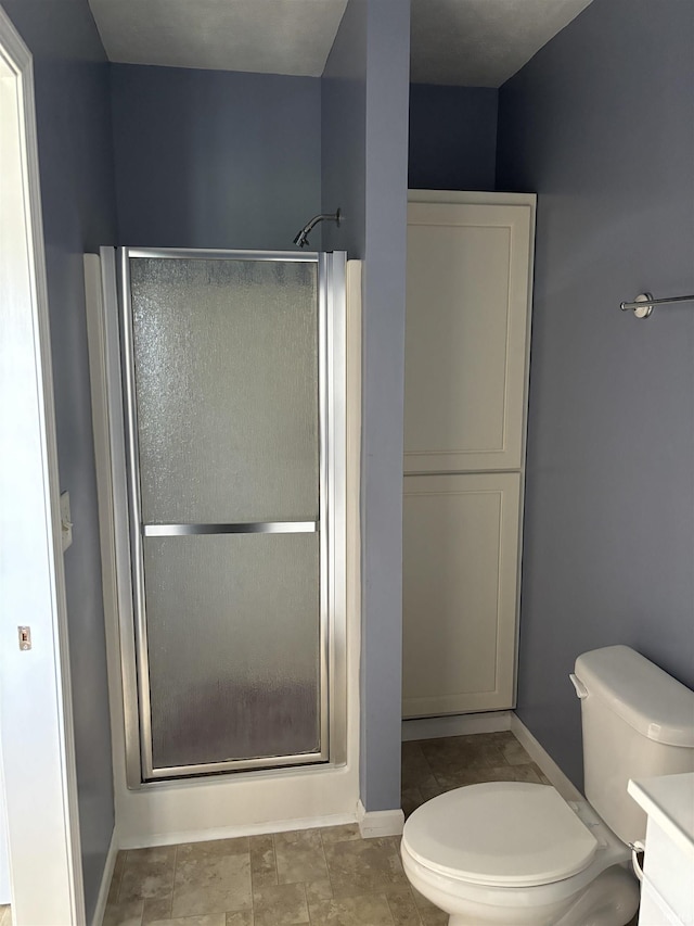 bathroom featuring a stall shower, baseboards, and toilet