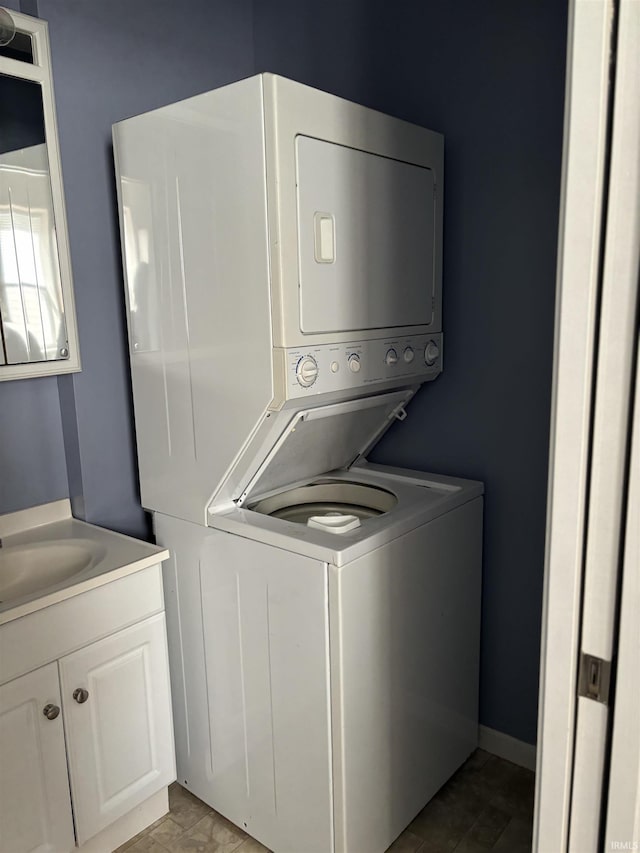 clothes washing area with stacked washer and dryer, laundry area, and a sink