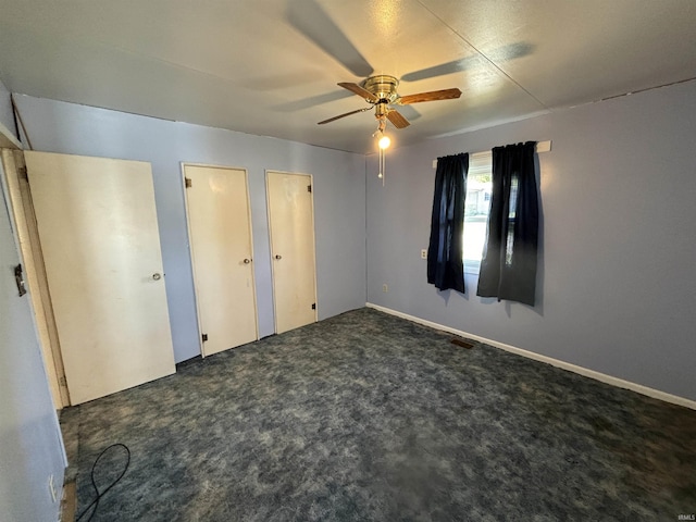 unfurnished bedroom featuring two closets, carpet, visible vents, and a ceiling fan