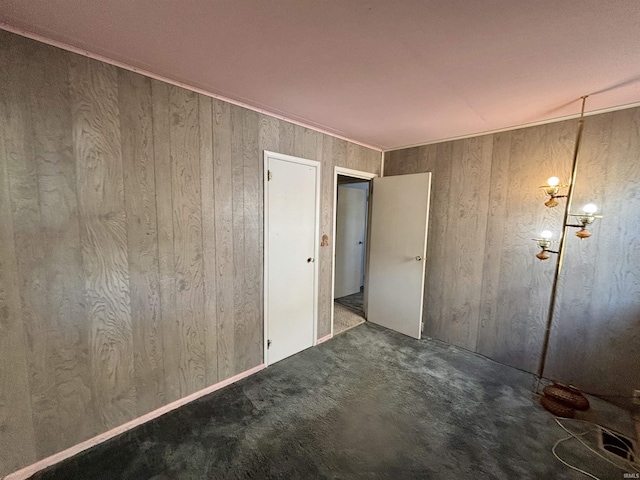 unfurnished bedroom featuring wood walls and carpet flooring