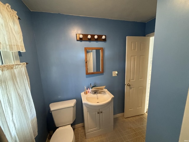 bathroom featuring baseboards, vanity, toilet, and tile patterned floors