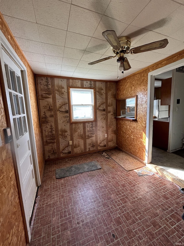 miscellaneous room featuring a paneled ceiling, brick floor, and a ceiling fan