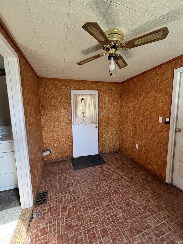 unfurnished room with brick patterned floor, visible vents, and a ceiling fan