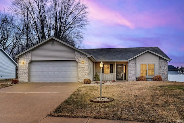 ranch-style home featuring covered porch, driveway, brick siding, and a garage