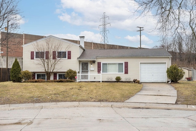 tri-level home with a garage, a shingled roof, concrete driveway, a front lawn, and a chimney