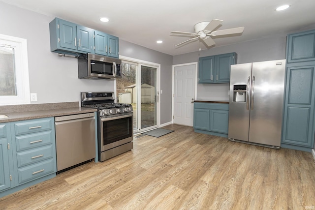 kitchen featuring a ceiling fan, light wood-style flooring, stainless steel appliances, blue cabinetry, and recessed lighting