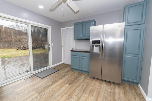 kitchen with baseboards, light wood-style floors, stainless steel refrigerator with ice dispenser, and blue cabinets