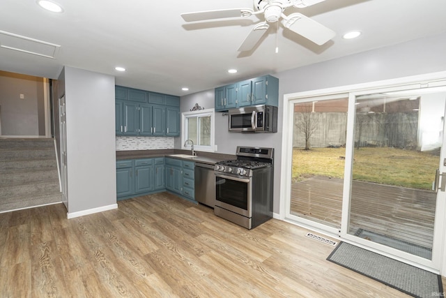 kitchen with blue cabinets, visible vents, stainless steel appliances, and a sink