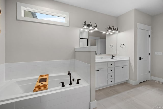 bathroom with a garden tub, vanity, and baseboards