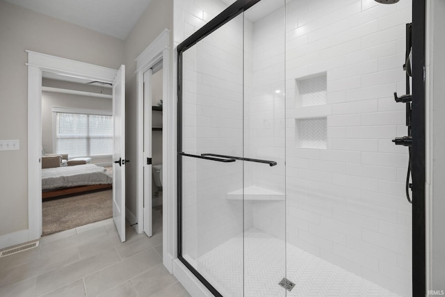 ensuite bathroom featuring toilet, a stall shower, and tile patterned flooring