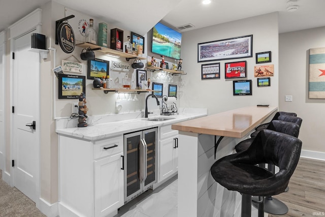 bar featuring wine cooler, indoor wet bar, visible vents, a sink, and baseboards