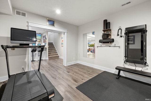 exercise room featuring baseboards, visible vents, and wood finished floors