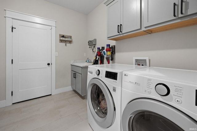 laundry area with washing machine and dryer, cabinet space, and baseboards