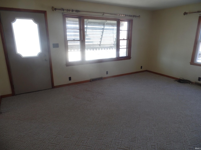 empty room with carpet, visible vents, and baseboards