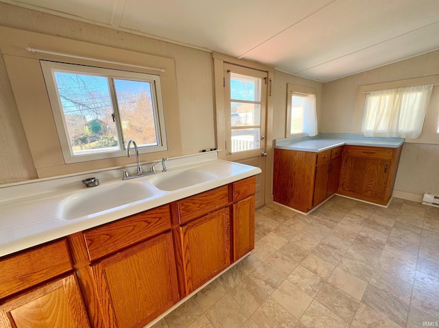 kitchen with lofted ceiling, light countertops, a sink, and brown cabinets