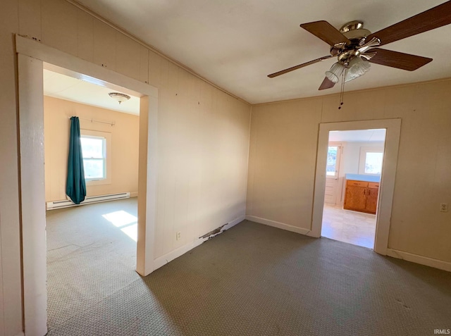 carpeted empty room with crown molding, a baseboard radiator, ceiling fan, and baseboards