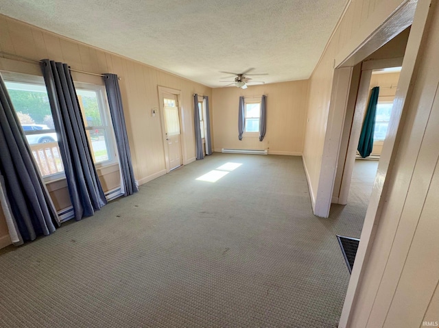 unfurnished room featuring a baseboard heating unit, a textured ceiling, visible vents, and light colored carpet