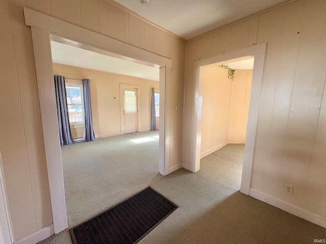 corridor featuring carpet, wooden walls, visible vents, and baseboards