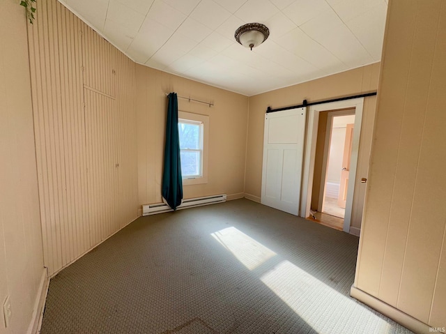 unfurnished bedroom featuring a barn door, wood walls, a baseboard radiator, and carpet flooring