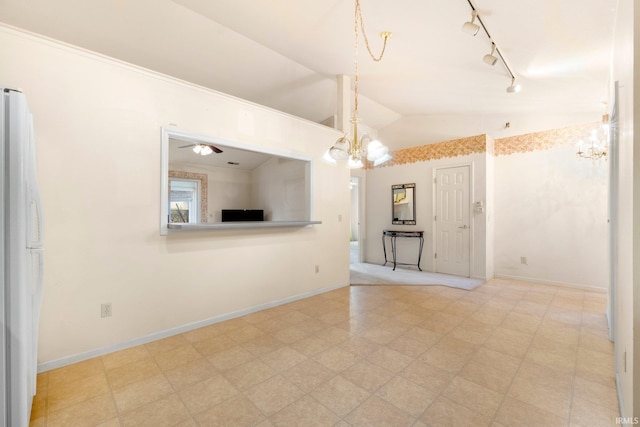 unfurnished living room with vaulted ceiling, track lighting, baseboards, and an inviting chandelier