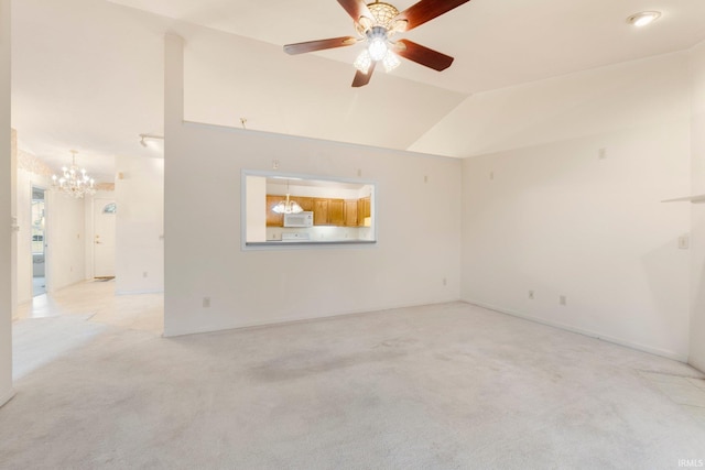 empty room featuring ceiling fan with notable chandelier, vaulted ceiling, and light colored carpet