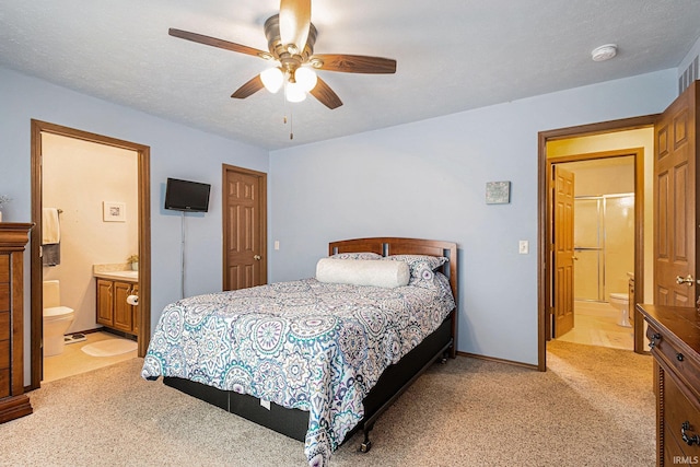 bedroom featuring light carpet, ceiling fan, a textured ceiling, and ensuite bath