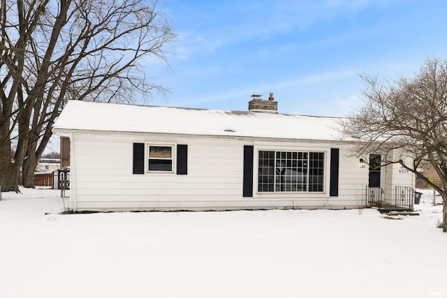 snow covered property with a chimney